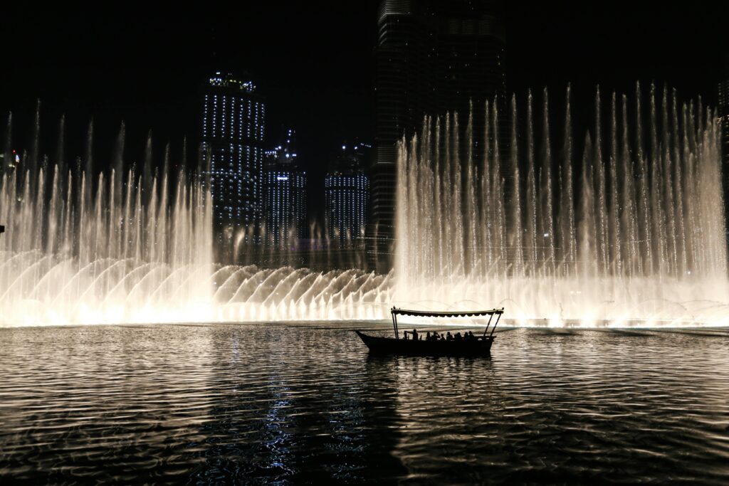 pexels-photo-692104-692104 Silhouette of a boat against the illuminated Dubai Fountain at night, showcasing the city skyline.